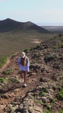 Sarışın, güzel bir kadın turistin volkanik ovalarda gerçek zamanlı olarak yürüdüğü dikey video.
