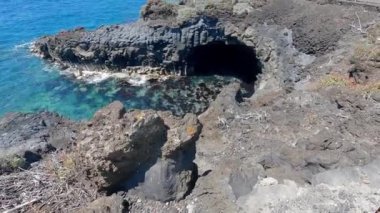 Evleri ve mağaraları olan güzel volkanik kıyı manzarasının gerçek zamanlı görüntüsü.