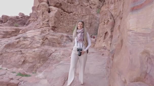ヨルダンでペトラを訪れる道を幸せに歩くブロンドの女性のゆっくりとした動きの横のビデオ — ストック動画