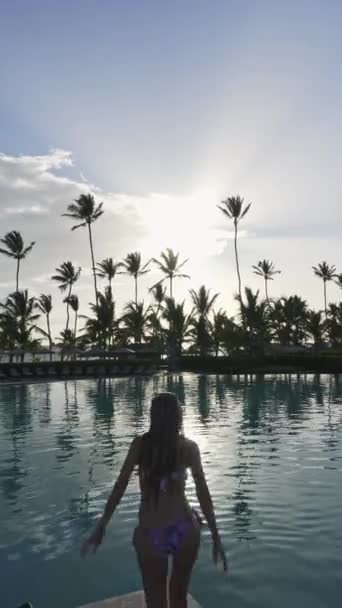 Günbatımında Palmiye Ağaçlarıyla Çevrili Lüks Bir Yüzme Havuzunda Havuza Atlayan — Stok video
