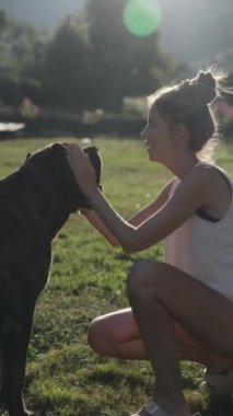 Bir kadın güneşli bir tarlada sert bir kanarya köpeğiyle oynaşmaktan zevk alır. Gülüşlerini ve sevgi dolu etkileşimlerini paylaşıyorlar. Huzurlu bir ortamda bağlarını sergiliyorlar..