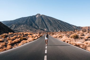 Çölde Teide özgeçmişi olan bir kadın yürüyor. Yol boş ve gökyüzü temiz.