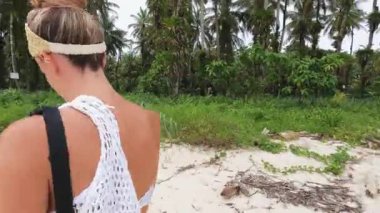 Seksi bikinili sarışın kadın cennette yürüyor vahşi tropikal beyaz plajda. Seyahat gezisindeki güzel fit vücut kızı