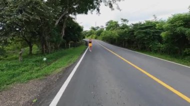 4K video. Asfalt yolda yürüyen genç sarışın kadın. Panama, Amerika 'da arka planda dağlar