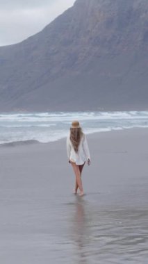 Bir kadının kıyı boyunca yürüyüp, güneş dağların ardından batarken ayaklarının üzerinde yıkanan soğuk suyu hissederken Lanzarote 'deki Famara' da huzurlu bir atmosfer yaratıyor..