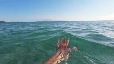POV insanın rahatlatıcı elleri. Güneşli bir günde plajda berrak suda yüzmenin huzurunu hisset..