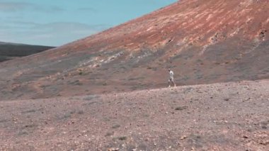 Yalnız bir yürüyüşçü, Lanzarote 'de berrak gökyüzünün altındaki volkanik bir bölgenin çorak arazisini araştırır..