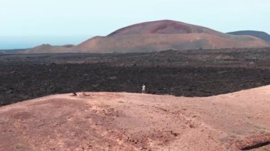 Bir adamın insansız hava aracı yörüngesi Timanfaya Ulusal Parkları 'nı keşfediyor. Nefes kesici volkanik manzaralar ve çarpıcı jeolojik renkler..