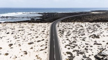 El değmemiş kumlar ve kayalık kıyı şeridi ile çevrili çarpıcı bir kıyı yolu Mojon Blanco, Lanzarote 'da doğal güzellik ve dingin manzaralar sergiliyor.