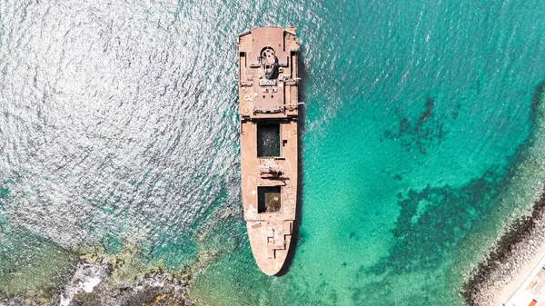 Arrecife, Lanzarote 'de sakin sularla çevrili, berrak bir gökyüzünün altında, kıyı şeridi yakınında büyük paslı bir gemi enkazı duruyor.