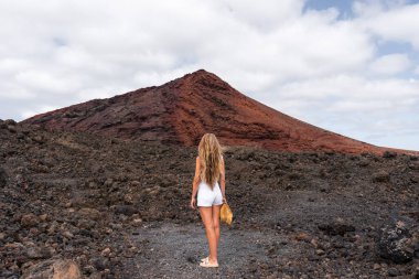 Uzun saçlı bir kadın Lanzarote 'deki siyah lav tarlalarıyla çevrili Bermeja dağına bakıyor.