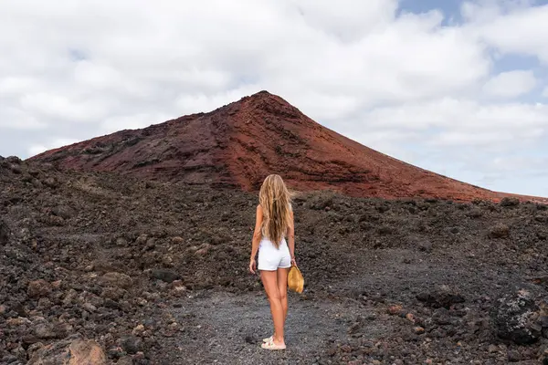 Uzun saçlı bir kadın Lanzarote 'deki siyah lav tarlalarıyla çevrili Bermeja dağına bakıyor.