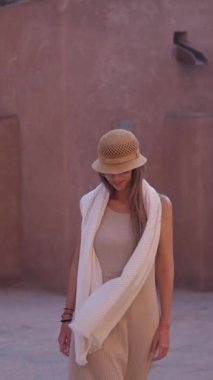 Sarışın bir kadının ağır çekimde sıcak tonlu bir alanda zarif bir şekilde dolaşması ve güneş ışığının tadını çıkarması..