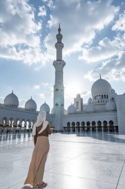 Abu Dabi, Birleşik Arap Emirlikleri 'nde bulutlu bir gökyüzünün altında Şeyh zayed Büyük Camii' ne hayran olan bir turist.