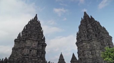 Orta Cava, Endonezya 'daki antik Prambanan tapınağı, mavi gökyüzüne karşı karmaşık taş oymalar ve yüksek yapılar sergiliyor.