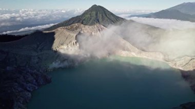 Turkuaz sülfürik su ve volkanik gaz salgılayan fümerollü ijen Dağı krater gölü havadan görünüyor.
