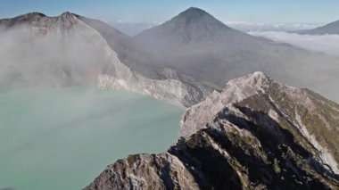 Kawah ijen volkanik kraterindeki turkuaz sülfür gölünün havadan görüntüsü yükseliyor.