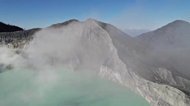 Endonezya 'daki Kawah ijen volkanik kraterinin içinde turkuaz sülfür gölü ve fümeroller.