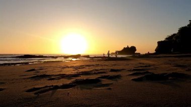 Zaman aşımına uğramış turistler Tanah tapınağında gün batımının keyfini çıkarıyorlar, Bali
