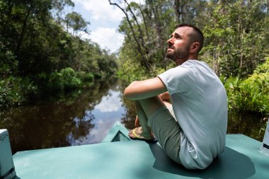 Turist, Tanjung tropikal nehrinde dinlendirici bir tekne gezisinin keyfini çıkarıyor. Ulusal park, Kalimantan, Endonezya