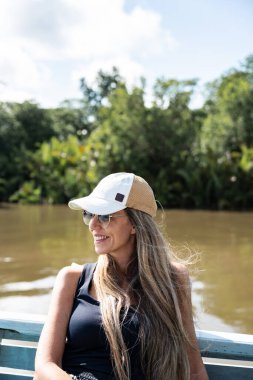 Borneo, milli parktaki tekne gezisinde gülümseyen ve eğlenen bir turist