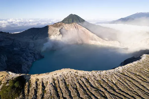 Turkuaz sülfürik asit gölü ve fümeroller Kawah ijen volkanı kraterinde duman oluşturuyor.