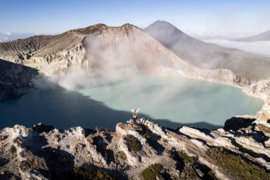 Drone View Turist Doğu Java, Endonezya 'daki Kawah ijen yanardağının turkuaz sülfür gölünün önünde kollarını kaldırıyor