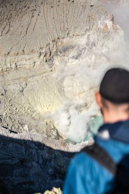Doğu Java, Endonezya 'daki Kawah ijen volkanı krateri içinde sülfürik sülfürik asit gölü ve sülfür dumanı yayan volkanolog gözlemliyor.