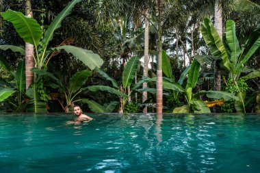 İnsanoğlu, egzotik orman manzarasının ortasında sonsuz havuzda ferahlatıcı bir yüzüşün tadını çıkarıyor.