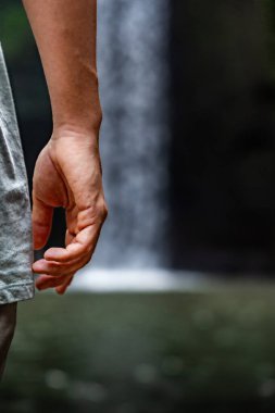 Arka planda tropikal bir yağmur ormanında şelalesi olan bir turistin yakın çekimi