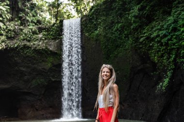 Genç sarışın kadın Endonezya, Bali 'de tropik bir şelalenin tadını çıkarıyor.