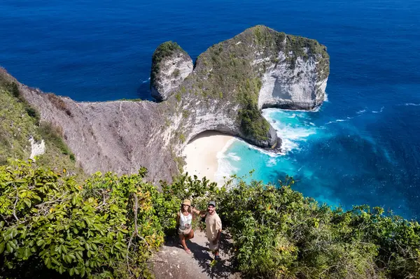Çift, Kelingking plajının nefes kesici manzarasının keyfini çıkarıyor. Nusa Penida, Bali, Endonezya 'da gizli bir mücevher.