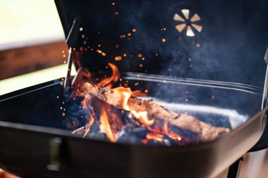 Izgaranın içinde yanan odun kıvılcımlar ve duman yaratır, ızgaraya hazır.