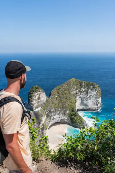 Sırt çantalı kelingking plajlarının simgesel t-rex şekilli uçurumlarının ve Nusa Penida 'nın turkuaz sularının nefes kesici manzarasının tadını çıkarıyor.