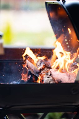 Ahşap odunlar yanıyor, kor oluşturuyor ve ızgarada duman çıkıyor, pişirmeye hazır.