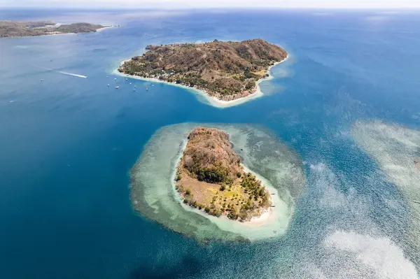 Komodo Ulusal Parkı 'ndaki turkuaz su ve mercan resifleriyle çevrili iki adanın hava görüntüsü.