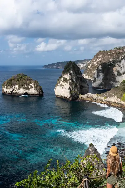 Sarışın turist, Nusa Penida, Bali 'deki elmas plaj ve turkuaz suyun nefes kesici manzarasına hayran.