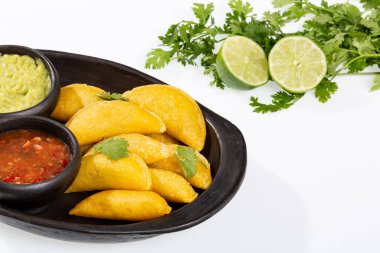 Beyaz arka planda baharatlı sos ve guacamole soslu Kolombiya Empanadası.