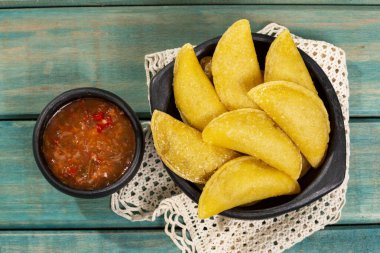 Tahta zemin üzerinde acı sos ile Kolombiya Empanadası.