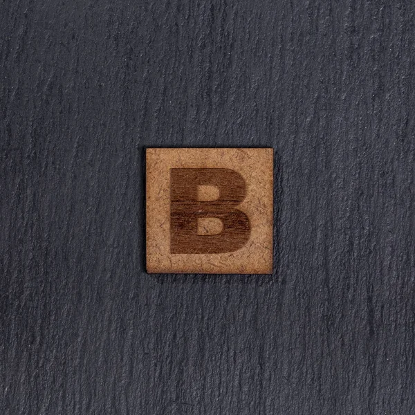 正方形の木製のタイルで大文字 手紙B 黒の石の背景に — ストック写真