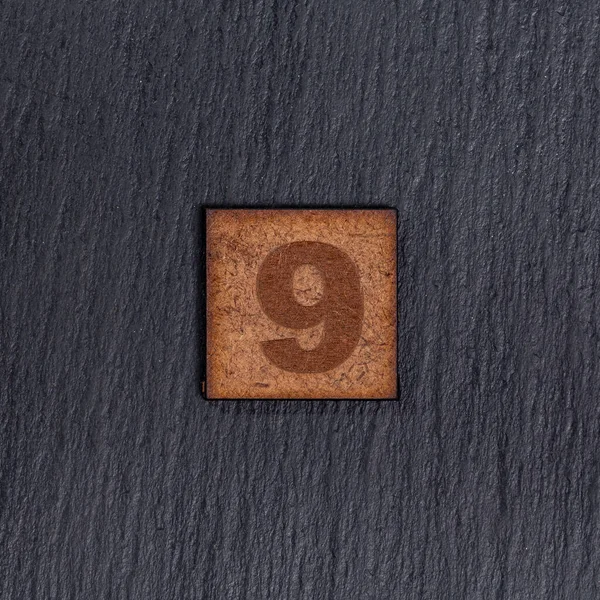 正方形木製のタイルの数 番号9 ブラックストーンの背景に — ストック写真