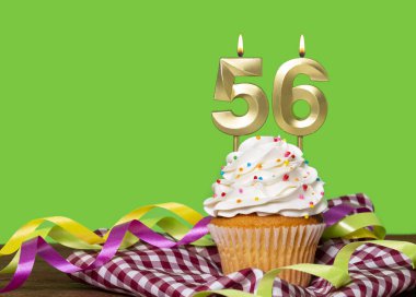 Yeşil Arkaplanda 56 numaralı mumlu doğum günü pastası.