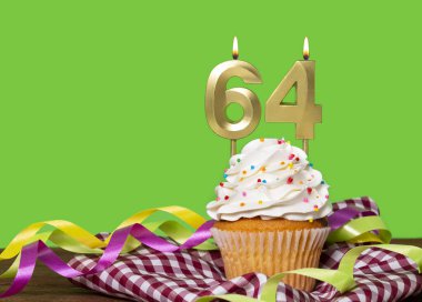 Yeşil Arkaplanda 64 numaralı mumlu doğum günü pastası.