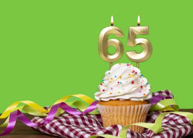 Yeşil Arkaplanda 65 Numaralı Mumlu Doğum Günü Pastası.