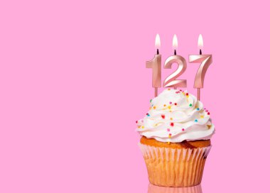 127 numaralı mumlu doğum günü pastası Pembe Arkaplanda.