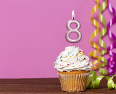 Pembe Arkaplanda 8 numaralı mumlu doğum günü pastası.