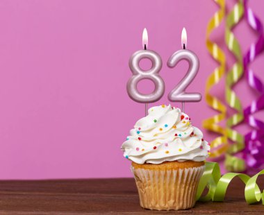 82 Numaralı Mumlu Doğum Günü Pastası Pembe Arkaplanda.
