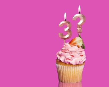 3 numaralı mumlu doğum günü pastası ve sıcak pembe arka plandaki soru işareti..