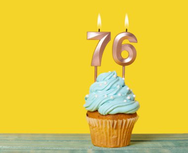 Sarı Arkaplanda 76 Numaralı Mumlu Doğum Günü Pastası.