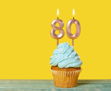 Sarı Arkaplanda 80 numaralı mumlu doğum günü pastası.
